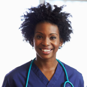 Black female nurse with short hair smiling wearing blue scrubs with a stethoscope around her neck